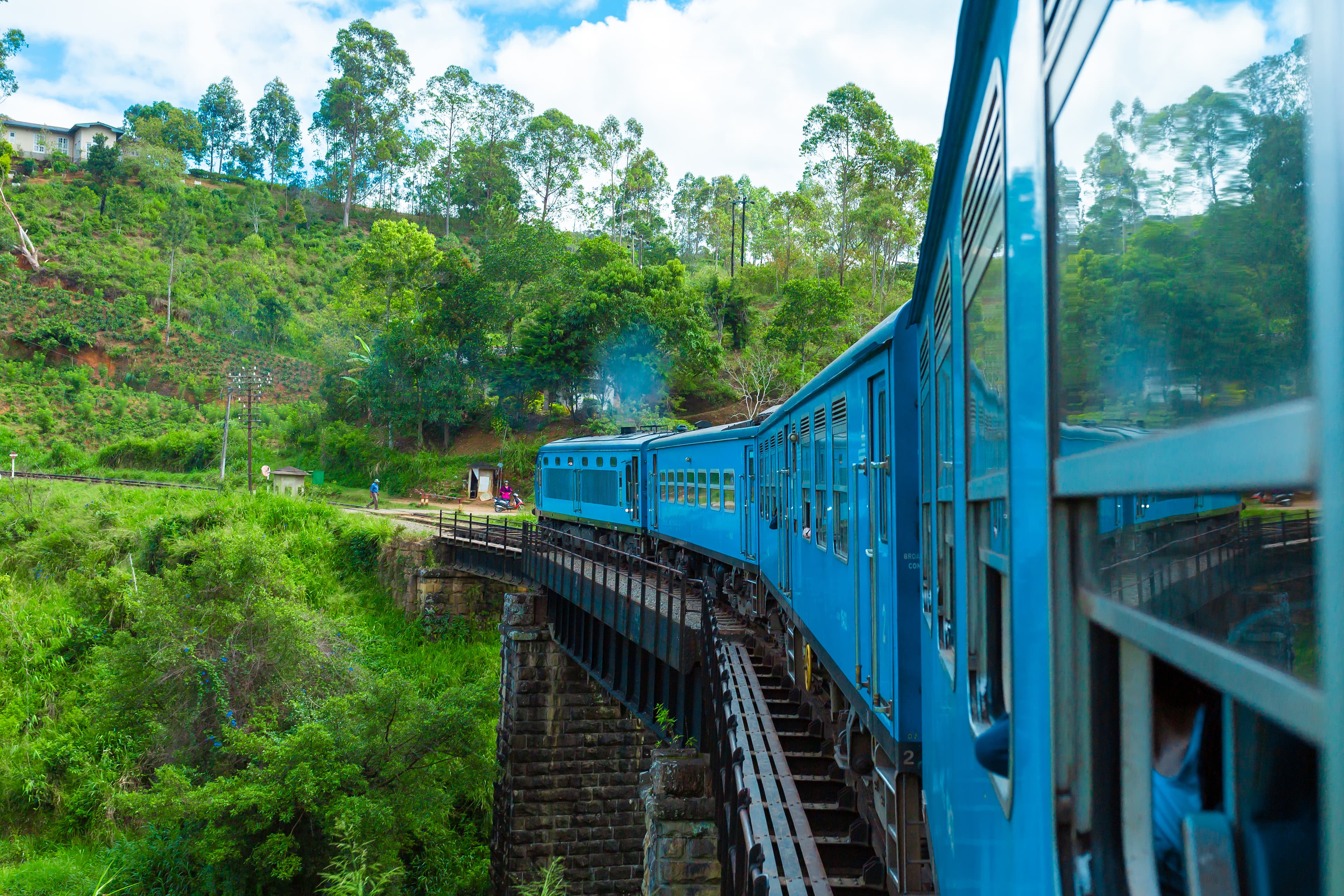 Blue passenger train winding through dense tropical jungle on the iconic Sri Lanka highland railway